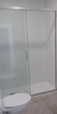 a bathroom with a toilet and a glass shower at Apartamentos Turísticos Magencio in Carucedo