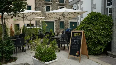 a restaurant with tables and chairs with umbrellas at Pensión Castro Parrillada in Samos