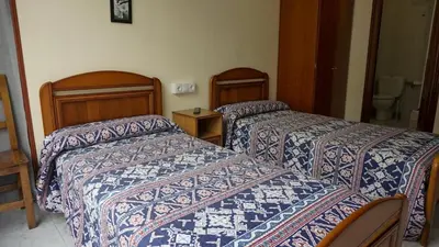 a hotel room with two beds and a toilet at Pensión Castro Parrillada in Samos