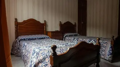 a bedroom with two beds with blue and white sheets at Pensión Castro Parrillada in Samos