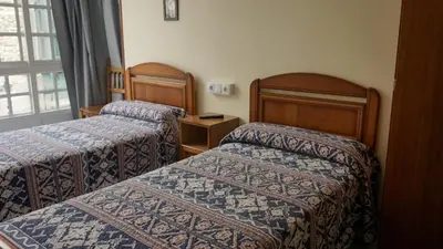 a hotel room with two beds and a window at Pensión Castro Parrillada in Samos