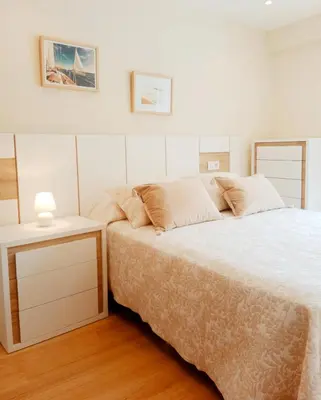 a white bedroom with a bed and a night stand at Casa Lolita 1 in Viveiro