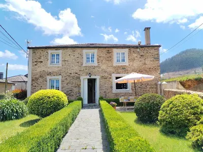 a stone house with a garden and an umbrella at Casa Lolita 1 in Viveiro