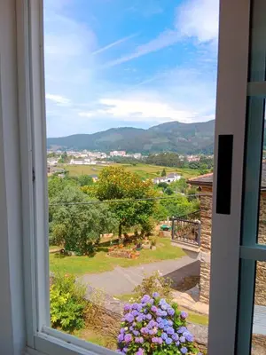 a window with a view of a garden and mountains at Casa Lolita 1 in Viveiro