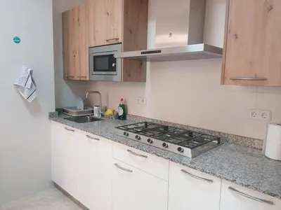 a kitchen with white cabinets and a stove top oven at Albergue El Templarin in Ponferrada