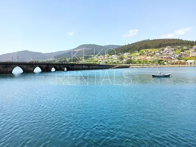 a boat in the water next to a bridge at Ribeira in Vivero