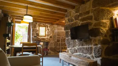 a living room with a stone wall with a tv at Casa la Trinidad - Ribeira Sacra in Nogueira de Ramuin