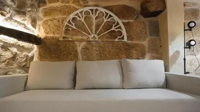 a couch in a room with a stone wall at Casa la Trinidad - Ribeira Sacra in Nogueira de Ramuin