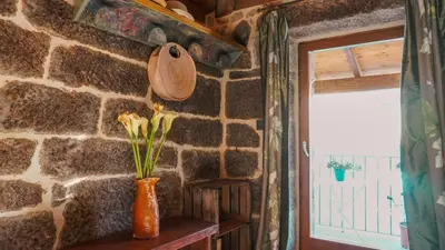 a room with a stone wall and a vase with flowers at Casa la Trinidad - Ribeira Sacra in Nogueira de Ramuin