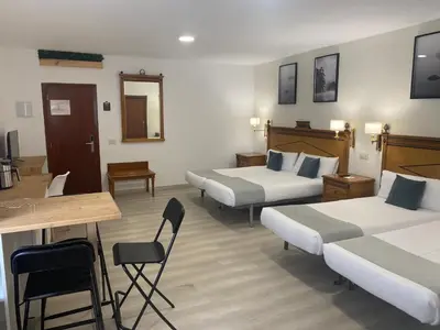 a hotel room with three beds and a table and chairs at Alda Cabanas Playa in Cabañas