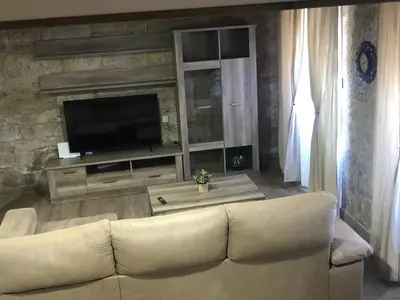 a living room with a couch and a flat screen tv at A Casa de Abaixo in Cuntis