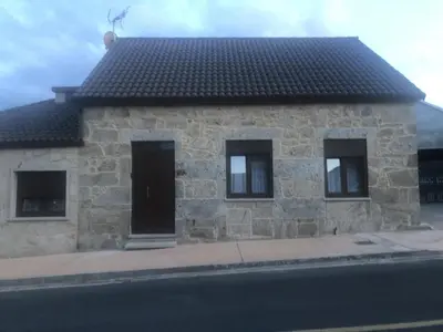 a stone house on the side of a street at A Casa de Abaixo in Cuntis
