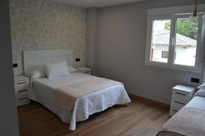 a white bedroom with a bed and a window at Greco 8 in Sarria