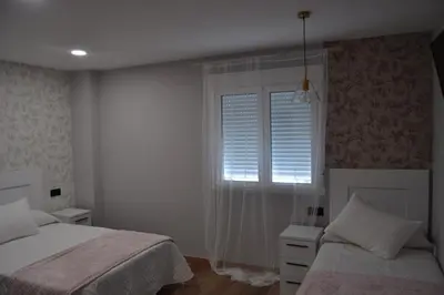 a bedroom with two beds and a window with blinds at Greco 8 in Sarria