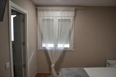 a bedroom with a bed and a window with curtains at Greco 8 in Sarria