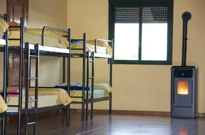 a room with three bunk beds and a fire place at Albergue los Blasones in Sarria