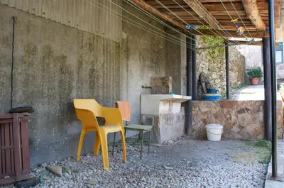 a patio with two chairs and a table and a stove at Albergue los Blasones in Sarria