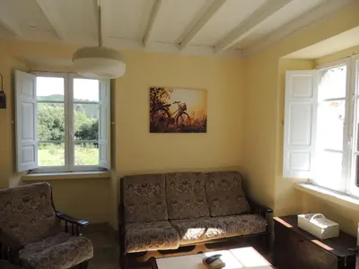 a living room with a couch and two windows at Casa de Campo Pumarada de Oirín in Foz