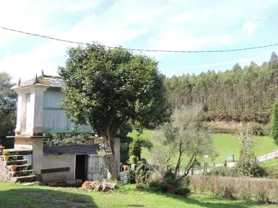 an old house in a field with a tree at Casa de Campo Pumarada de Oirín in Foz