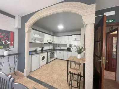 a kitchen with white cabinets and a table with chairs at Toxiños Lavacolla in A Coruña