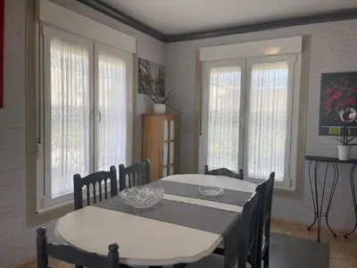 a dining room with a table and chairs and windows at Toxiños Lavacolla in A Coruña