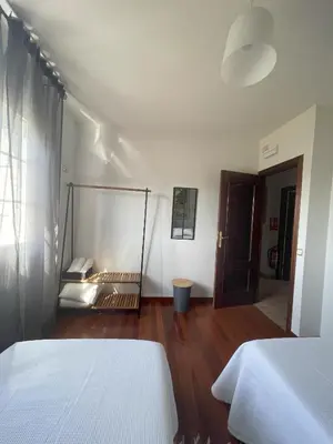 a white bedroom with two beds and a wooden floor at Toxiños Lavacolla in A Coruña
