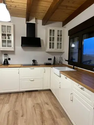 a kitchen with white cabinets and a wooden floor at Casa El Santanderino in El Espino
