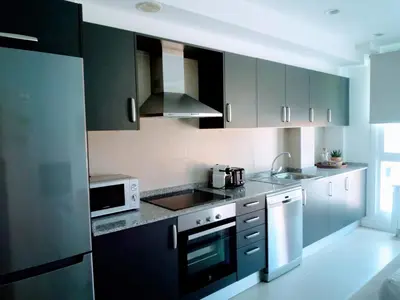 a kitchen with black cabinets and white appliances at Apartamento en Sada con Piscina in Sada