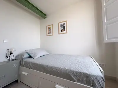 a bedroom with a bed and a white wall at Apartamentos Ribadeo in Ribadeo