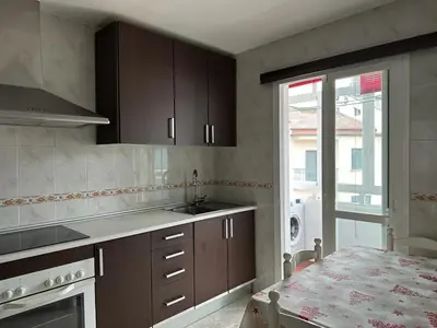 a kitchen with brown cabinets and a sink and a table at Ensino 22 in Ourense