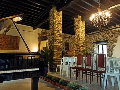a room with a piano and chairs and a chandelier at Santa Emilia in Mondoñedo