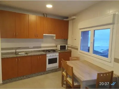a kitchen with wooden cabinets and a table and a window at CANTABRICO in Barreiros