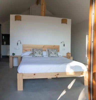 a bedroom with a large wooden bed with two pillows at O rincón dos Sentidos in Cenlle