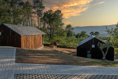 two barns with the sunset in the background at O rincón dos Sentidos in Cenlle