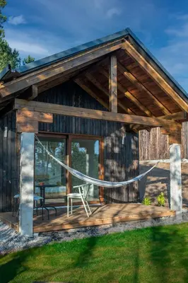 a log cabin with a deck with a swing at O rincón dos Sentidos in Cenlle