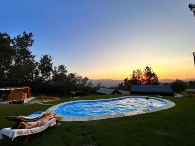 a couple laying in the grass next to a swimming pool at O rincón dos Sentidos in Cenlle
