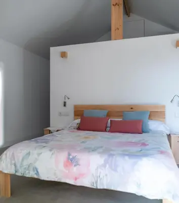 a bedroom with a large bed with pink and blue pillows at O rincón dos Sentidos in Cenlle