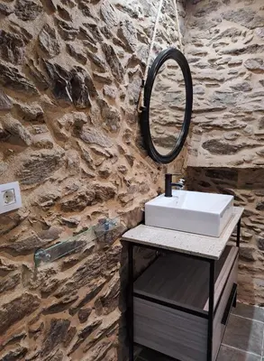 a bathroom with a sink and a mirror on a stone wall at CASA ARABIA in Monforte de Lemos