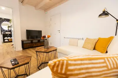 a living room with a white couch and a tv at Apartamentos Gurugú in Ribadeo