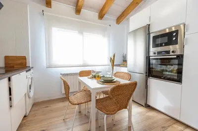 a kitchen with a white table and chairs in a room at Apartamentos Gurugú in Ribadeo