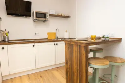 a kitchen with white cabinets and a counter with stools at Apartamentos Gurugú in Ribadeo
