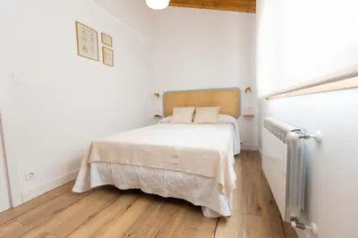a white bedroom with a bed and a radiator at Apartamentos Gurugú in Ribadeo