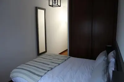 a bedroom with a white bed with a mirror at Apartamentos Camino Inglés in Ordes