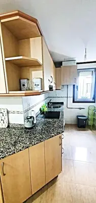 a kitchen with a washing machine and a table with chairs at Apartamentos Camino Inglés in Ordes