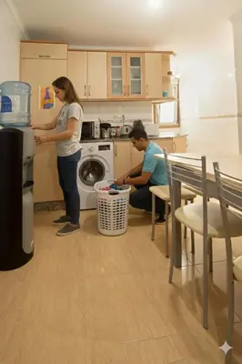 a man and a woman in a kitchen with a washing machine at Apartamentos Camino Inglés in Ordes