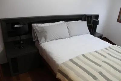 a bed with white sheets and pillows in a room at Apartamentos Camino Inglés in Ordes