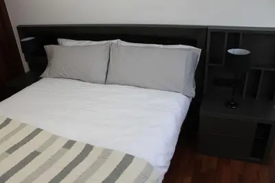 a bed with white sheets and pillows in a room at Apartamentos Camino Inglés in Ordes