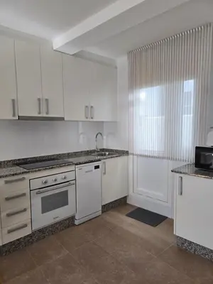 a kitchen with white cabinets and a sink and a window at Pote in Lugo