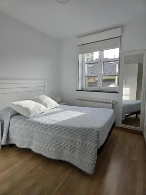 a white bedroom with a large bed and a window at Pote in Lugo