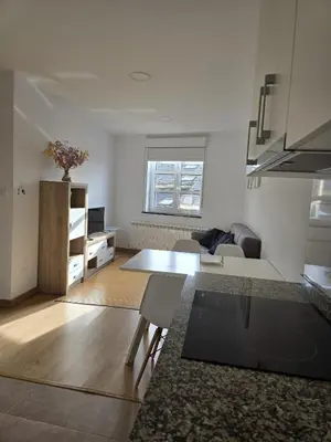 a living room with a table and a kitchen at Pote in Lugo